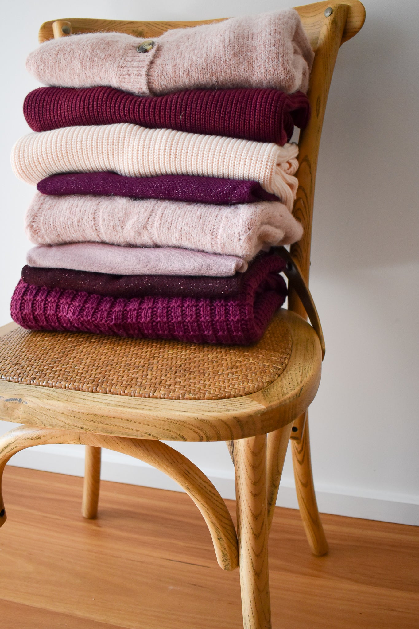 A stack of women's knitwear in berry tones